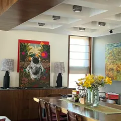The 'Recuperation' painting installed in its new home, a modern dining area. The artwork's vivid colors and surreal imagery bring a unique energy and conversation point to the space.