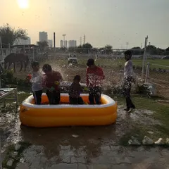 Kids splashing in an inflatable pool at sunset during a Holi party. It's a fantastic way to cool down and have fun.