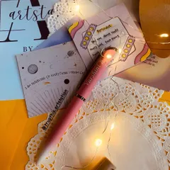 A personalized pen makes for a classy and affordable gift. This beautiful pink and white ombre pen is engraved with the name "Varshini B" and is surrounded by fairy lights and affirmation cards.