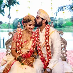 An intimate and tender moment during a traditional South Indian wedding ceremony. The groom's gentle kiss on the bride's forehead captures the pure emotion of the day.