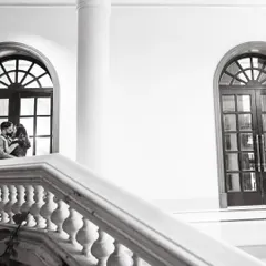 A stunning architectural shot in black and white, with the couple framed by a grand arched window. This creates a dramatic, cinematic, and elegant portrait.
