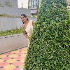 Saree is love, and a blouse from Taarini is an emotion. Here I am peeking from behind a bush, wearing a simple off-white natural crepe saree with a vibrant, full-sleeve printed blouse.