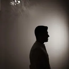A creative silhouette of the groom, his profile outlined against a single spotlight, creating a moody and sophisticated portrait.