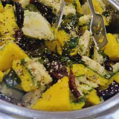 A close-up of soft, spongy Gujarati khaman dhokla, tempered with mustard seeds, curry leaves, and sesame. This is a light and popular snack for high-tea or breakfast meetings.
