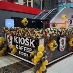 Balloon decor isn't just for entrances. Here, I used smaller balloon clusters in the brand's colors to decorate the kiosk itself, adding a festive touch to the point of sale and creating great photo opportunities.