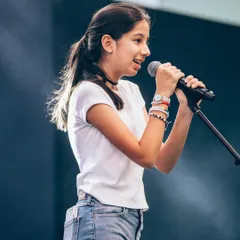 A confident young vocalist captivating the audience at Art Mumbai. Our vocal training focuses on helping students find their voice and perform with heart.