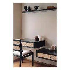 This floating study desk in a guest bedroom is a great solution for small spaces. Made of black burnt wood with cane-front drawers, it is paired with a matching chair. The design is sleek, functional, and uses natural materials to add warmth.