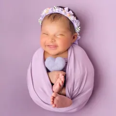 That sweet, sleepy smile says it all. In my posed newborn sessions, I use soft wraps and simple props against a vibrant backdrop to create beautiful, artful portraits of your little one's pure happiness.