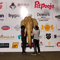 Taking our art on the road. Here, our team members are posing with the finished cardboard elephant head in front of a partner wall at an event, showing how our creations can serve as unique brand activations.
