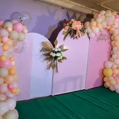 This backdrop for Thoshini's first birthday featured a custom-shaped panel in pink, decorated with beautiful floral pieces and two asymmetrical balloon garlands. The setup is perfect for stage photos and cake cutting.