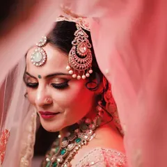 A close-up of one of our brides, capturing the dreamy, romantic look we created. This artistic shot highlights the detailed eye makeup, flawless skin finish, and the perfect placement of traditional jewelry, all essential for a timeless bridal portrait.