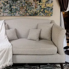 A custom-designed sofa from our House of Goya collection, upholstered in a classic houndstooth fabric. It's a timeless piece that can anchor a room with its sophisticated pattern and elegant silhouette.