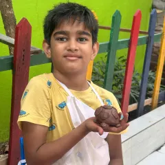 A young sculptor proudly showing off his handmade clay turtle. These workshops are designed to help kids turn their ideas into tangible masterpieces.
