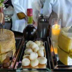 An elegant cheese grazing station, featuring wheels of aged cheese, fresh mozzarella balls, and balsamic vinegar. This setup offers a sophisticated start to the meal, perfect for pairing with crackers and dips.