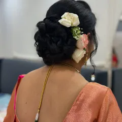 An elegant and classic low bun adorned with fresh roses. This timeless hairstyle is perfect for a saree look and keeps you comfortable all day.
