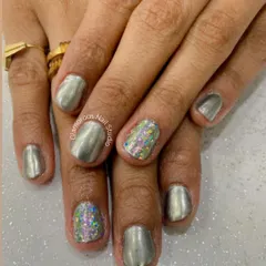 Modern and chic. This manicure features a sleek, metallic silver chrome polish on most nails, with two accent nails covered in a stunning multi-colored holographic glitter.