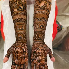 A classic bridal mehendi for Gayatri, featuring portraits of the couple on the palms during the varmala ceremony. The forearms are adorned with baraat scenes, including the groom on an elephant.