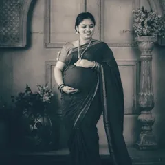 A solo portrait of the mother-to-be, radiating grace and strength. The studio setup with the pillar and archway adds a touch of architectural elegance, beautifully framing her as she cradles her baby bump.