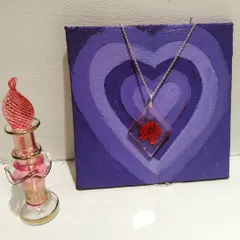 A diamond-shaped resin pendant featuring a vibrant red preserved flower. The clear resin magnifies the intricate details of the bloom inside.