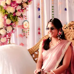 Capturing the bride's cool and candid side. Her relaxed pose with sunglasses amidst the floral decorations shows a fun, unscripted moment during her Haldi function.