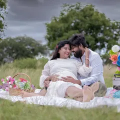 Another lovely picnic scene, this time with the couple sharing a happy moment. The open green field provides a beautiful, natural backdrop.