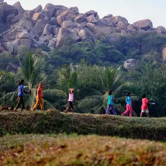 A line of local girls from a nearby village walks through the Hampi landscape. We love sharing the joy of climbing and the beauty of their own backyard with them.