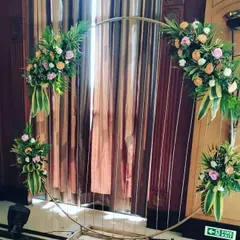 This photo shows a simple yet elegant circular metal frame decorated with four arrangements of fresh flowers and leaves. This kind of versatile backdrop can be used for any type of party and serves as a beautiful frame for photos.