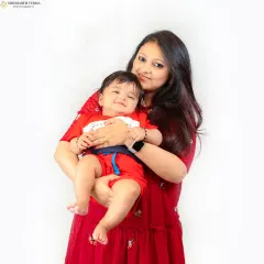 A mother holds her smiling baby close, both radiating warmth and happiness. This portrait, set against a simple white background, highlights their special connection.