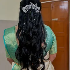For Rakshitha's reception, we created this beautiful half-up hairstyle with cascading waves and interwoven braids, finished with a delicate, sparkling floral hairpiece.