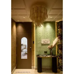 The foyer of our Duplex Project makes a grand statement with a textured green wall, a stunning chandelier, and a floral arrangement. It’s a warm and luxurious welcome for family and guests.