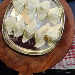 A tray of hand-folded samosas, filled with a spiced potato and pea mixture, ready for frying.