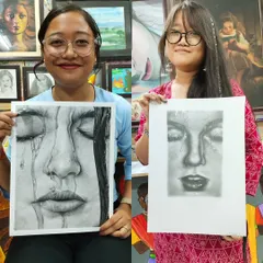 Two students proudly holding their hyper-realistic pencil portraits. It's amazing to see their progress and the incredible skill they develop.