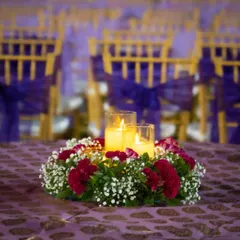 A close-up of our table centerpiece design, featuring warm candles surrounded by a wreath of fresh red and white flowers, adding a touch of romance to the guest tables.