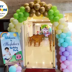 A welcoming entrance for a Cocomelon-themed first birthday, featuring a rainbow balloon arch and a personalized sign.