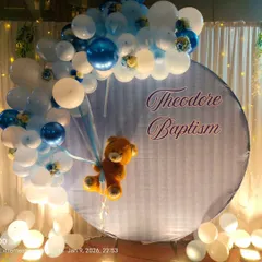 A charming teddy bear themed backdrop for a Baptism ceremony. This setup features a custom printed circular backdrop with the child's name, framed by a blue and white balloon arch, with a cute teddy bear appearing to float with balloons.