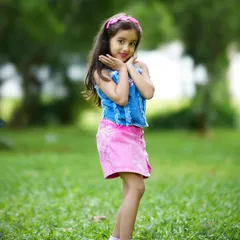 A pretty girl posing playfully in a park. Outdoor shoots are perfect for capturing the natural energy and joy of childhood.