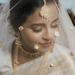A delicate and dreamy bridal portrait. The sheer veil with golden details adds a layer of softness to this close-up shot, capturing the bride's graceful and serene beauty.