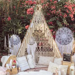 A stunning boho-chic teepee tent set up in a garden, creating a perfect, cozy spot for photos or relaxing.