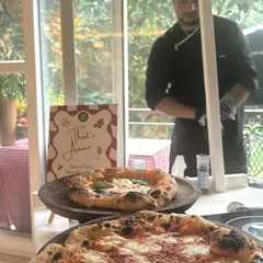 An intimate indoor pizza party setup. My chef works behind the counter with two fresh pizzas on display, showing how I can bring the full experience into your home.