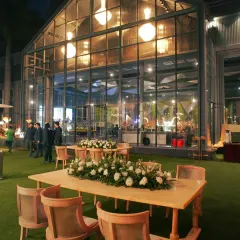 A modern glasshouse venue setup for an evening reception, showcasing the beautiful interplay of indoor and outdoor spaces.