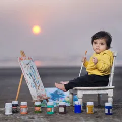 A mini artist creating a masterpiece on the beach at sunset. This themed outdoor shoot combines creativity with the beautiful natural backdrop of the sea and sky.