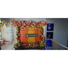 This is a simple stage-style decoration for a home Ganpati celebration. I used a backdrop of orange and yellow drapes with a floral border and fairy lights to create a warm and inviting space for pooja.