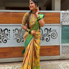 This beautiful yellow and green silk saree is paired with a heavily hand-embroidered gold blouse. The detailed work on the blouse elevates the entire look, making it perfect for a wedding ceremony.