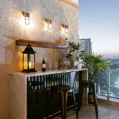 Your balcony can be the perfect spot for a home bar. I created this custom bar with a marble top and a corrugated metal front, paired with industrial-style stools and warm wall lighting to create a stylish space for evening drinks with a view.