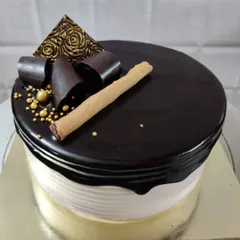 This chocolate drip cake is all about rich flavors and elegant decoration. It's topped with dark chocolate curls, golden sugar beads, a decorative chocolate piece, and a crunchy wafer roll.