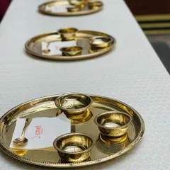 A close-up of the Royal Gold Thali. Each plate is set with matching katoris (bowls) and a custom-branded napkin, ensuring an elegant and personalized touch for every guest.