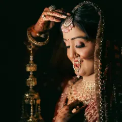 A classic bridal portrait with a focus on the bride's traditional jewelry and kaleeras. The low-key lighting creates a timeless and intimate feel, drawing attention to her serene expression.