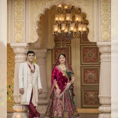 Framed by an ornate golden archway, the couple stands as a picture of elegance. This shot highlights the stunning details of both their attire and the palatial location.