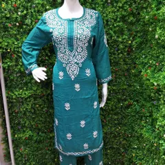 This teal green Chikankari suit set is displayed on a mannequin, showing the complete look with matching pants. The delicate white embroidery stands out against the rich color of the cotton fabric.