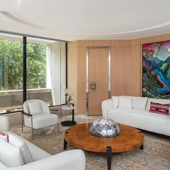 A lounge for directors on the second floor of 'The Layered Office'. The space is bright and airy, with light wood paneling, white furniture, and large windows that look out onto the building's central courtyard.